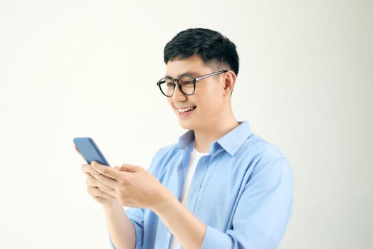 Relaxed young casual man reading text message on mobile phone isolated over white
