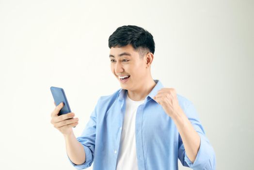 Image of excited happy young man posing isolated using mobile phone.
