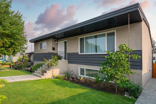 Average family house with concrete pathway over front yard. Residential house with landscaped front yard on golden hour sunset