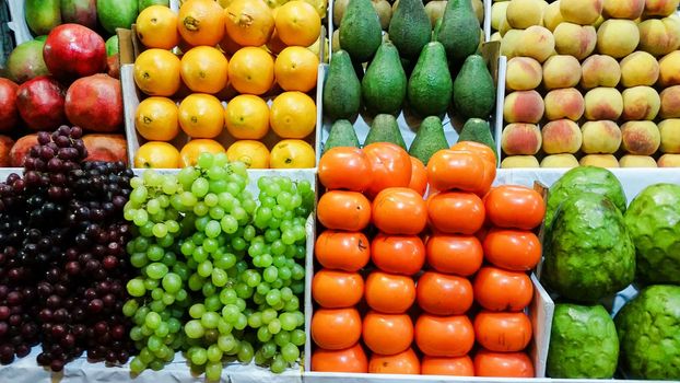 Assortment of fresh fruits and vegetables on market counter in a wooden boxes