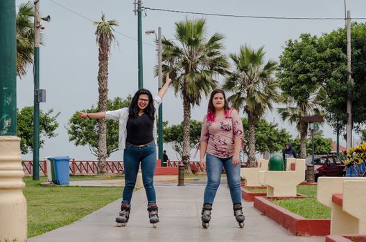 Two chubby girls with inline skates in the park happy