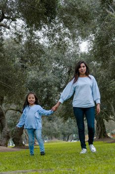 Mother and little Peruvian girl walking together in the park on an autumn afternoon