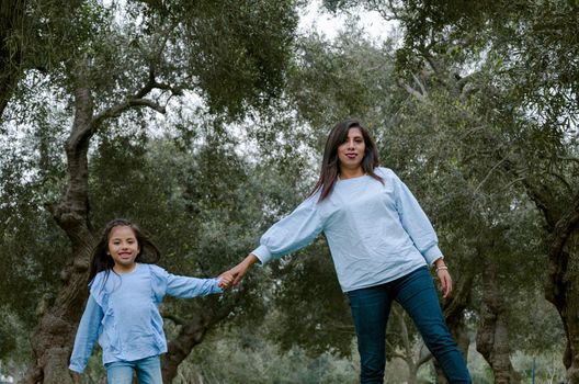 Mother and little Peruvian girl walking together in the park on an autumn afternoon