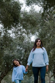 Mother and little Peruvian girl walking together in the park on an autumn afternoon