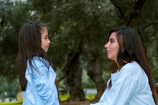 Mother and her little daughter looking at each other on a winter afternoon in the park