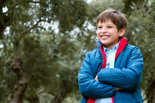 Portrait of a cute boy standing with arms crossed, smiling, looking at the camera