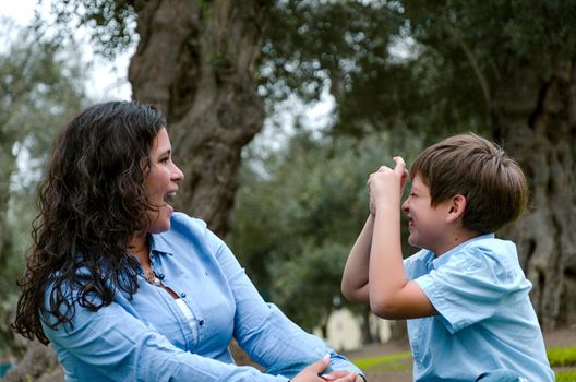 Beautiful woman and her cute little son looking at each other, son making the mimic of taking picture of the mother, the concept of wanting to take a picture