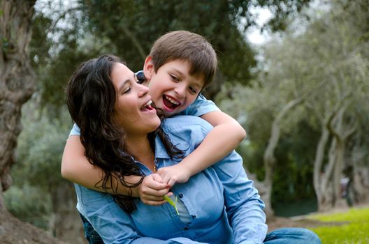 Child hugging his mother smiling on an autumn afternoon in the park