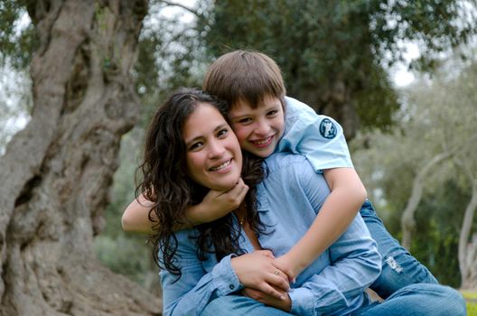 Child hugging his mother smiling on an autumn afternoon in the park