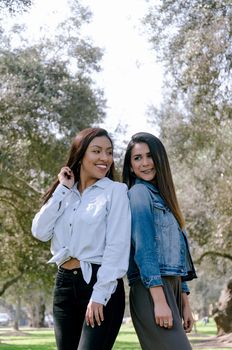 Two women best friends smiling over park background a day of autumn