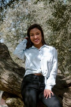 Beautiful young brunette woman leaning on the tree in the park