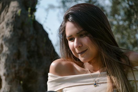 Beautiful smiling teenage girl, against green of summer park.