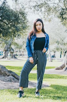 Young happy brunette woman in jeans jacket in the summer park