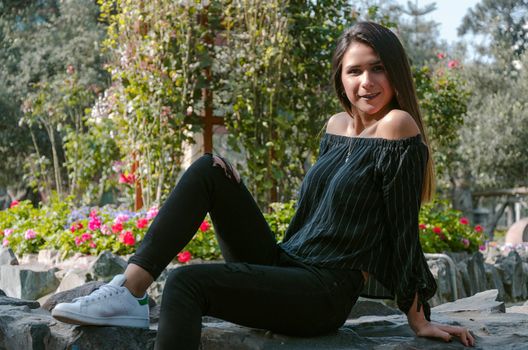 Sport fashion Girl sitting on rock in the green park