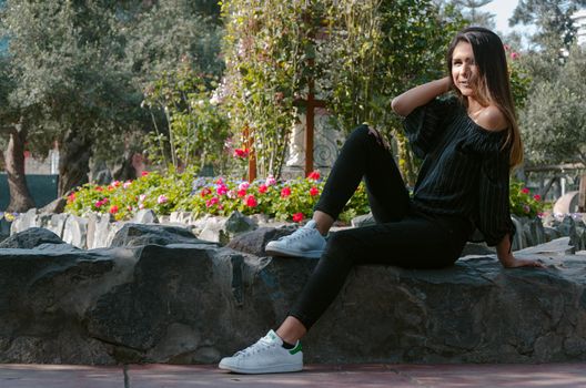 Sport fashion Girl sitting on rock in the green park