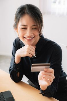 Cheerful woman smiling and holding credit card for online payment.