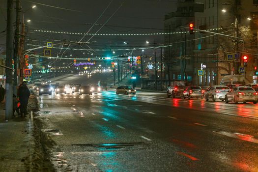Tula, Russia - December 20, 2020: Night automobile traffic on wide city street - close-up telephoto shot.