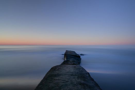 An old pier at the beach. Made of rocks and concrete.