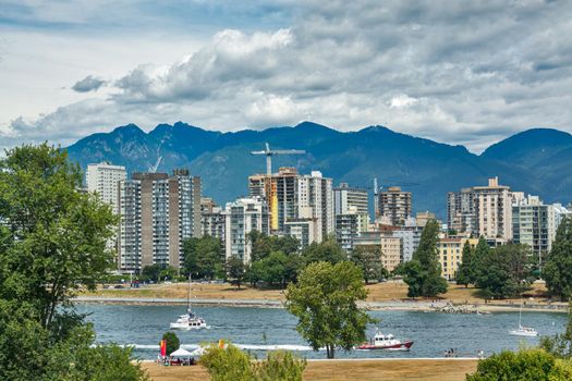 View on old part of Vancouver downtown over Coal harbor. Downtown view with mountains and cloudy sky on the background
