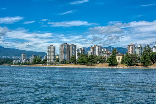 View on west part of Vancouver downtown over Coal harbor. Downtown view with mountains and cloudy sky on the background
