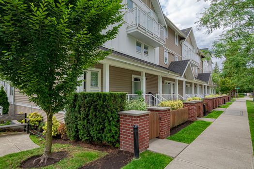 Row of townhouses with concrete pathway in front. Residential townhouses on cloudy day in Vancouver