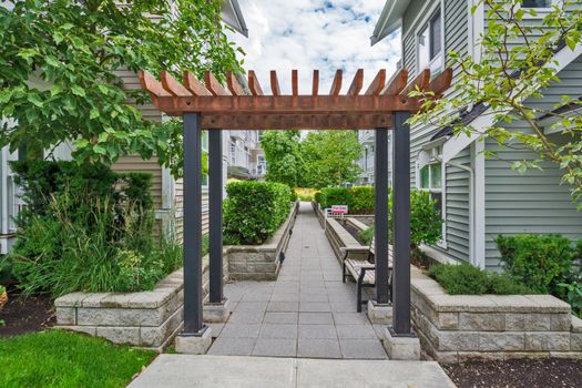 Quiet walkway in residential area between two rows of townhouses with one unit for sale