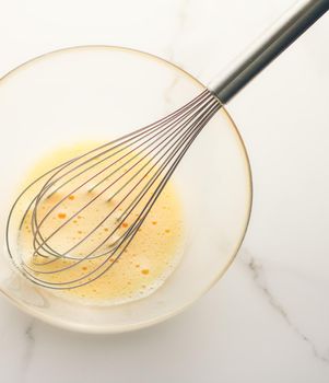 Cooking, meal and diet concept - Making of mixing eggs in bowl on marble table as homemade food flat lay, top view food brand photography flatlay and recipe for cooking blog, menu or cookbook design