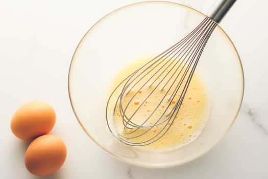 Cooking, meal and diet concept - Making of mixing eggs in bowl on marble table as homemade food flat lay, top view food brand photography flatlay and recipe for cooking blog, menu or cookbook design