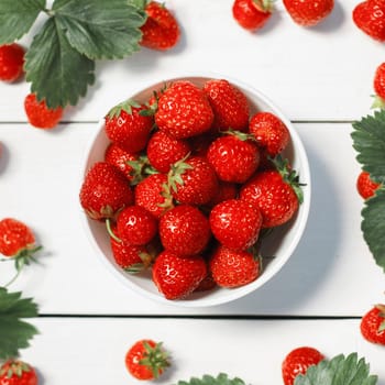 Fresh strawberries in a white porcelain bowl on wooden table in rustic style, selective focus