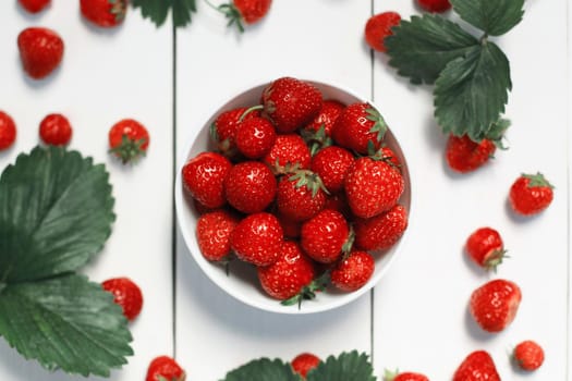 strawberry on a white wood background. selective focus on strawberries in the bowl