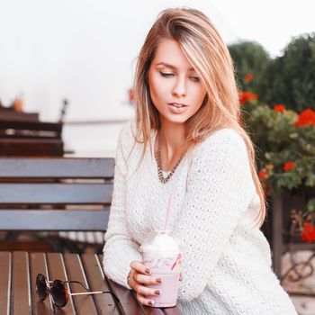 Portrait of a beautiful girl in a cafe. Drinks cocktail and relax.