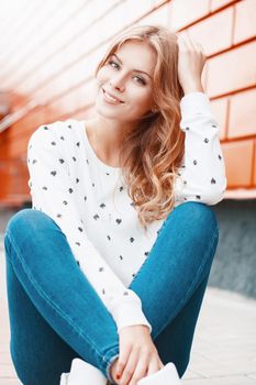 Beautiful portrait of a pretty smiling girl near stylish orange metal wall.