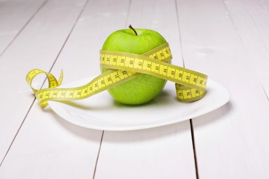 Apple with centimeter on the plate. Healthy eating