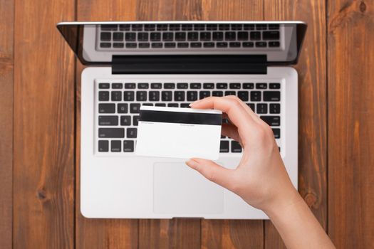 Female hand holding a card payment on a laptop