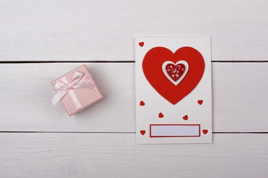 A gift and a card with red hearts on the table.