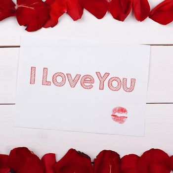 Sheet of paper for text I Love You with a kiss. Note and rose petals on the table
