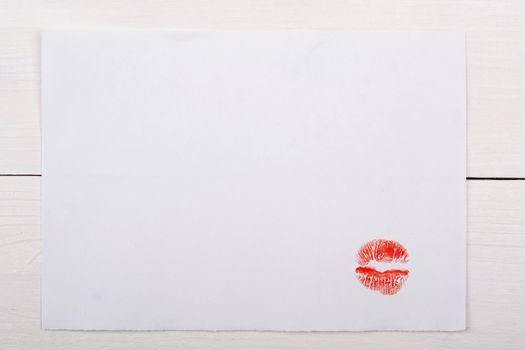 White sheet of paper with a kiss on a white table.