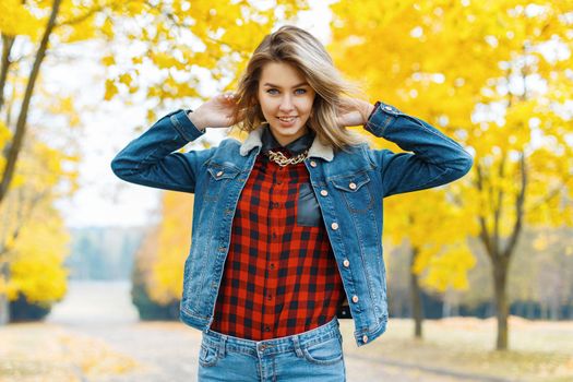 Young woman in jeans clothes in the autumn park.