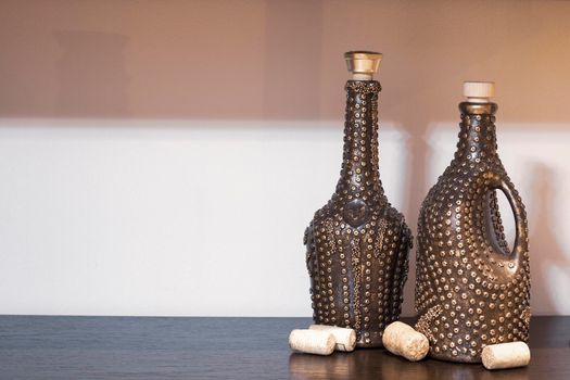 There are beautifully decorated wine bottles on the table and several corks lying nearby. Place for your text.