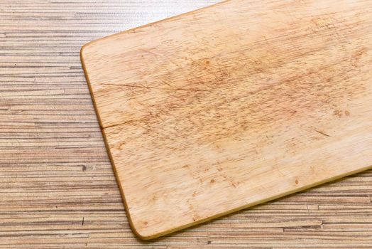 Old chopping board on wooden background top view.