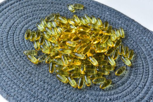 Bunch of omega 3 fish liver oil capsules in pile. Close up of big golden translucent pills texture. Healthy every day nutritional supplement. Top view.