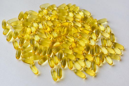 Bunch of omega 3 fish liver oil capsules in pile. Close up of big golden translucent pills texture. Healthy every day nutritional supplement. Top view.