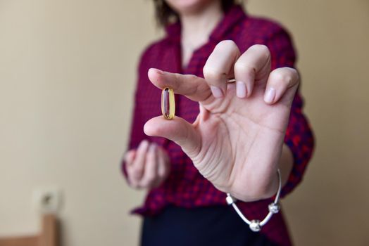 The woman in her hand holds a capsule of omega-3 fish oil. Medical healthcare, healthy food concept. Vitamin tablets.