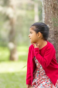 Little girl in flower dress and red sweater, very happy and smiling in the forest