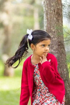 Little girl in flower dress and red sweater, very happy and smiling in the forest