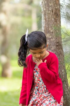 Little girl in flower dress and red sweater, very happy and smiling in the forest