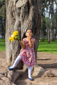 Little girl in dress celebrating in the park with a bouquet of flowers in her hand