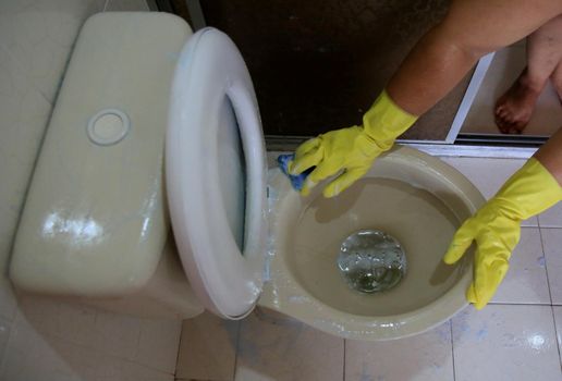 salvador, bahia, brazil - february 21, 2021: person wearing a rubber glove while cleaning a bathroom toilet in a residence in the city of Salvador.