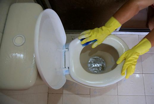 salvador, bahia, brazil - february 21, 2021: person wearing a rubber glove while cleaning a bathroom toilet in a residence in the city of Salvador.