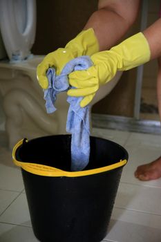 salvador, bahia, brazil - february 21, 2021: person wearing a rubber glove and holding a cloth next to a bucket while cleaning a bathroom in a residence in the city of Salvador.